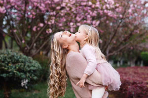 Mother laughing with child in her arms giving her a kiss